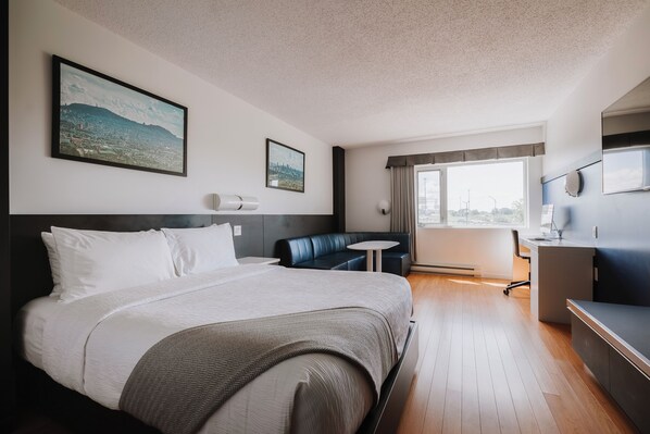 Una habitación de hotel con una cama grande, un escritorio, una silla, una mesita redonda y un televisor.