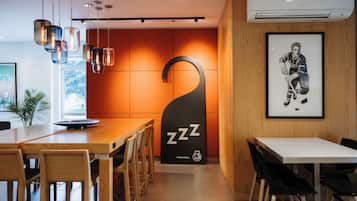 Una moderna hall d'albergo con una reception in legno, un grande poster incorniciato di un giocatore di hockey e un distintivo cartello nero con la scritta 'ZZZ'.