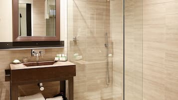 Une salle de bain moderne avec une douche à parois de verre, un meuble-lavabo en bois et un grand miroir.