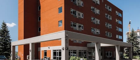 Un edificio de varios pisos con entrada cubierta y zona de estacionamiento.