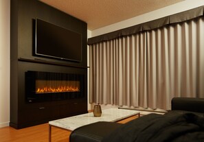 Una sala de estar moderna con un televisor de pantalla plana sobre una chimenea, un sofá y una mesa de centro.