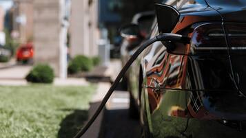A close-up of a car's rear with a charging cable connected to it.