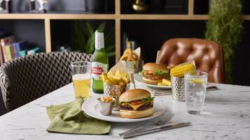 A dining table with a burger, fries, a drink, and a bottle of Stella Artois.