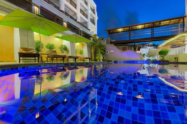 Una piscina al aire libre, sombrillas, sillones reclinables de piscina