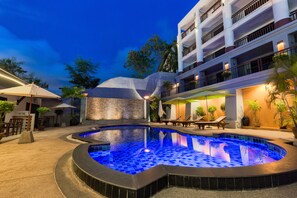 Una piscina al aire libre, sombrillas, sillones reclinables de piscina