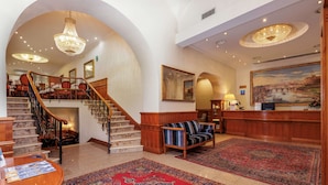 A grand lobby with a marble staircase, a reception desk, and a large painting of a cityscape. - Hotel Raffaello, Sure Hotel Collection by Best Western (Rome)