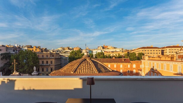 A terrace with a table and two chairs, overlooking a cityscape with historic buildings and a dome structure. - Hotel Raffaello, Sure Hotel Collection by Best Western (Rome)