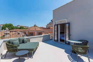 A rooftop terrace with a sofa, chairs, and a table.