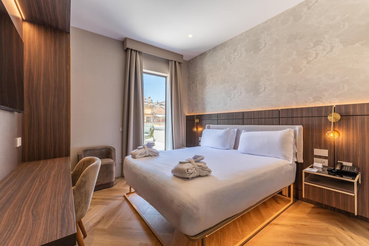 Una camera d'albergo con un letto, una scrivania, una sedia e vista all'esterno.