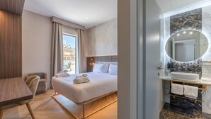 A modern hotel room with a bed, a desk, a chair, and a bathroom with a marble sink and mirror. - Hotel Raffaello, Sure Hotel Collection by Best Western (Rome)