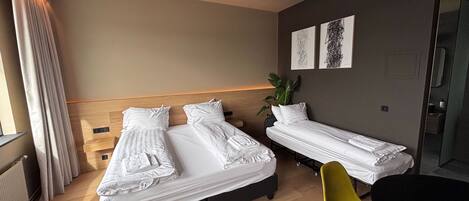 Habitación de hotel con dos camas, una mesita, una silla y una planta en maceta.
