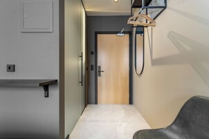 Un pasillo con una puerta de madera, un perchero y una estantería.