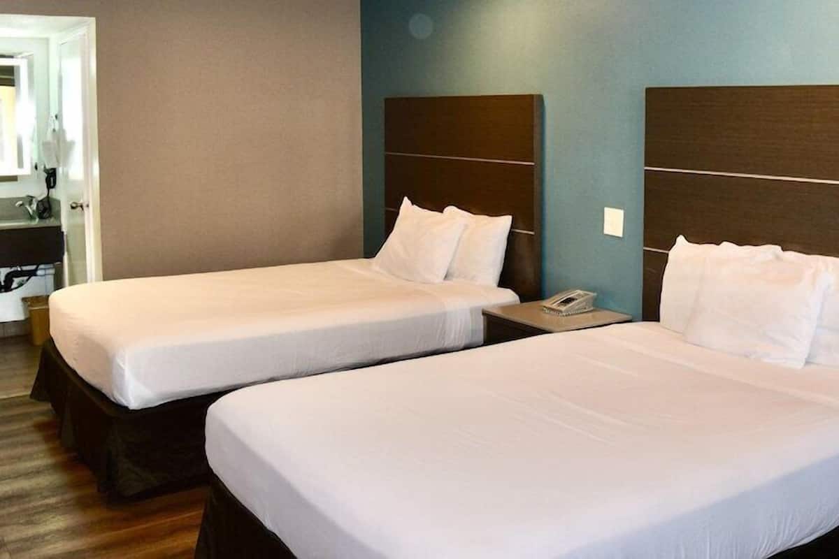 Två separata sängar med trägavlar i ett hotellrum.