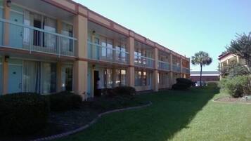 A multi-story motel with balconies, a well-maintained lawn, and a clear sky.