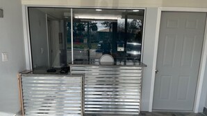 Entrada de hotel con una reja metálica, suelo de baldosas y una puerta blanca.