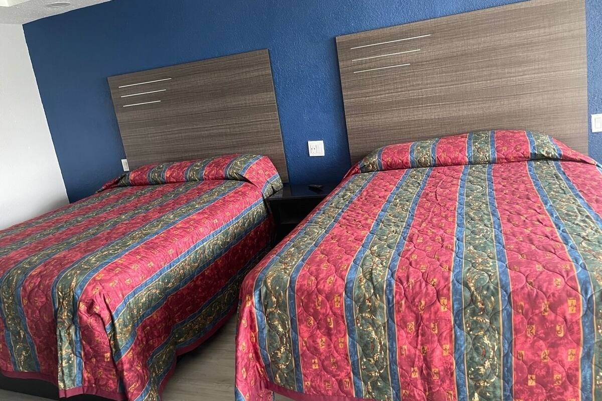 Ein Hotelzimmer mit zwei Betten, jeweils mit einem gemusterten Überwurf und Holz-Kopfteilen.