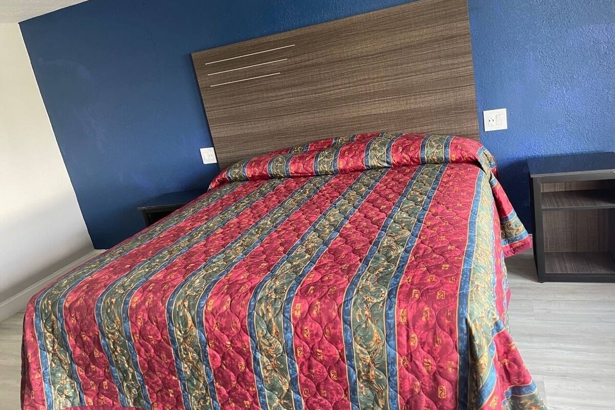 Ein Bett mit einem gemusterten Bettbezug, einem Holzkopfende und einem Nachttisch.