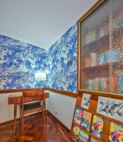 A room with a wooden desk, a chair, a large abstract painting, and a wall with a blue and white marbled pattern.