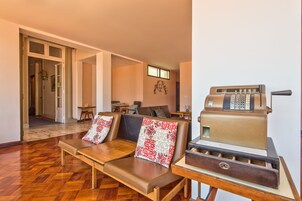 A room with a wooden bench, a vintage cash register, and a view of the hallway.