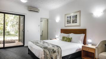 A hotel room with a bed, a nightstand, a chair, a door, and a window.
