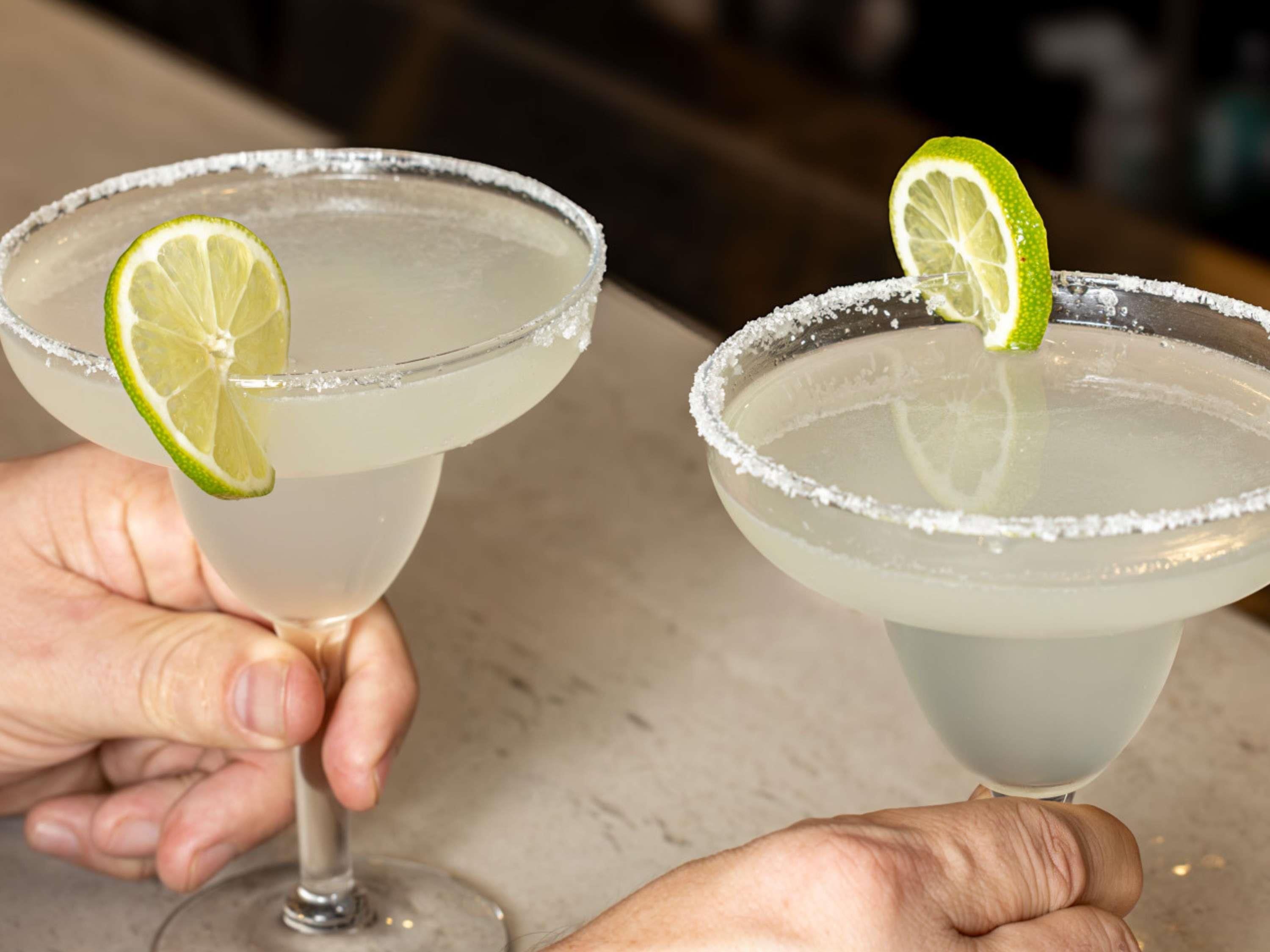 Two margarita glasses with lime garnishes and salt rims.