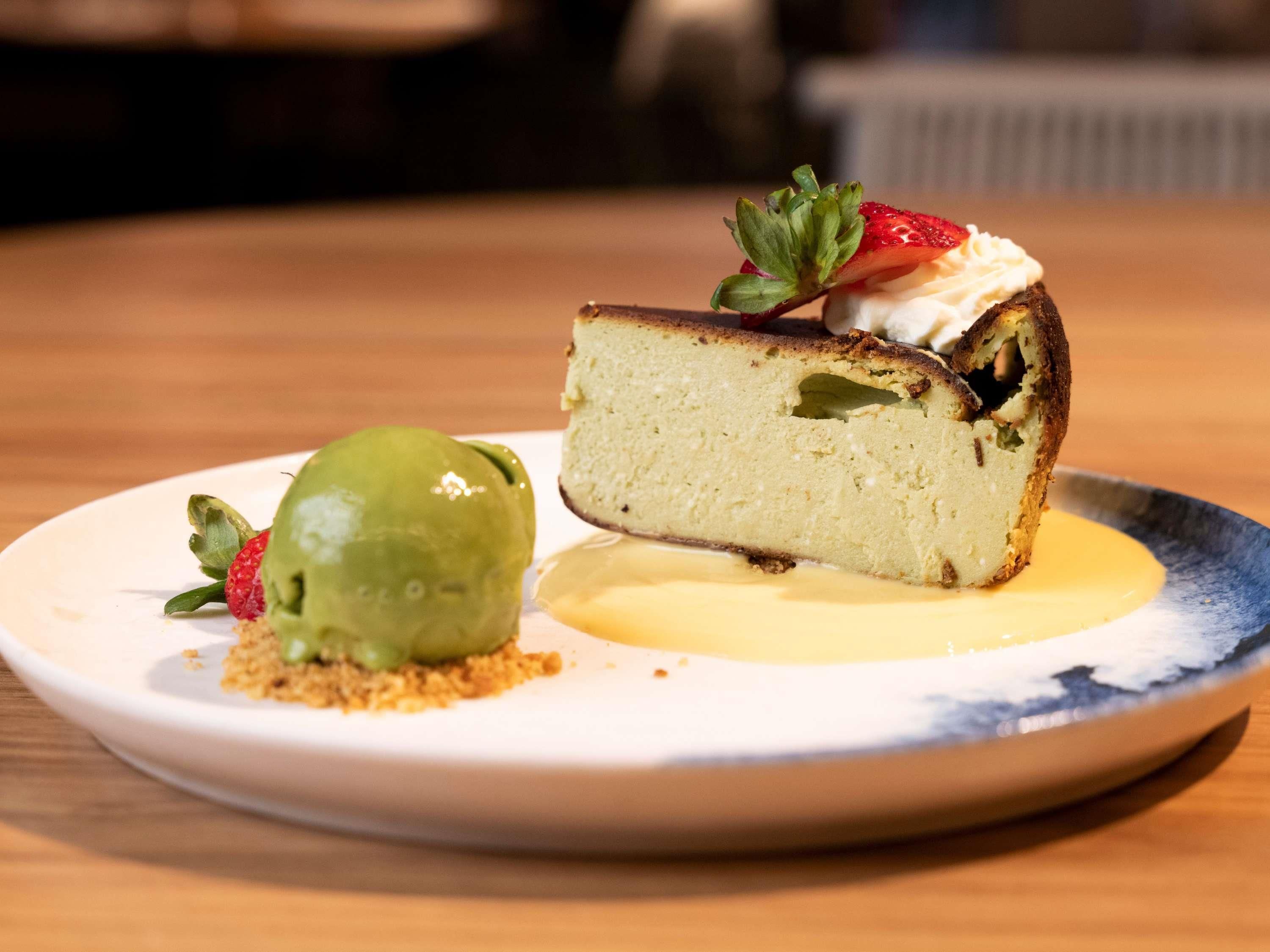 Une assiette à dessert avec une part de gâteau et un fruit vert, le tout présenté sur une assiette blanche à bordure bleue.
