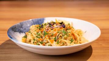A bowl of pasta with a creamy sauce and garnished with herbs and vegetables.
