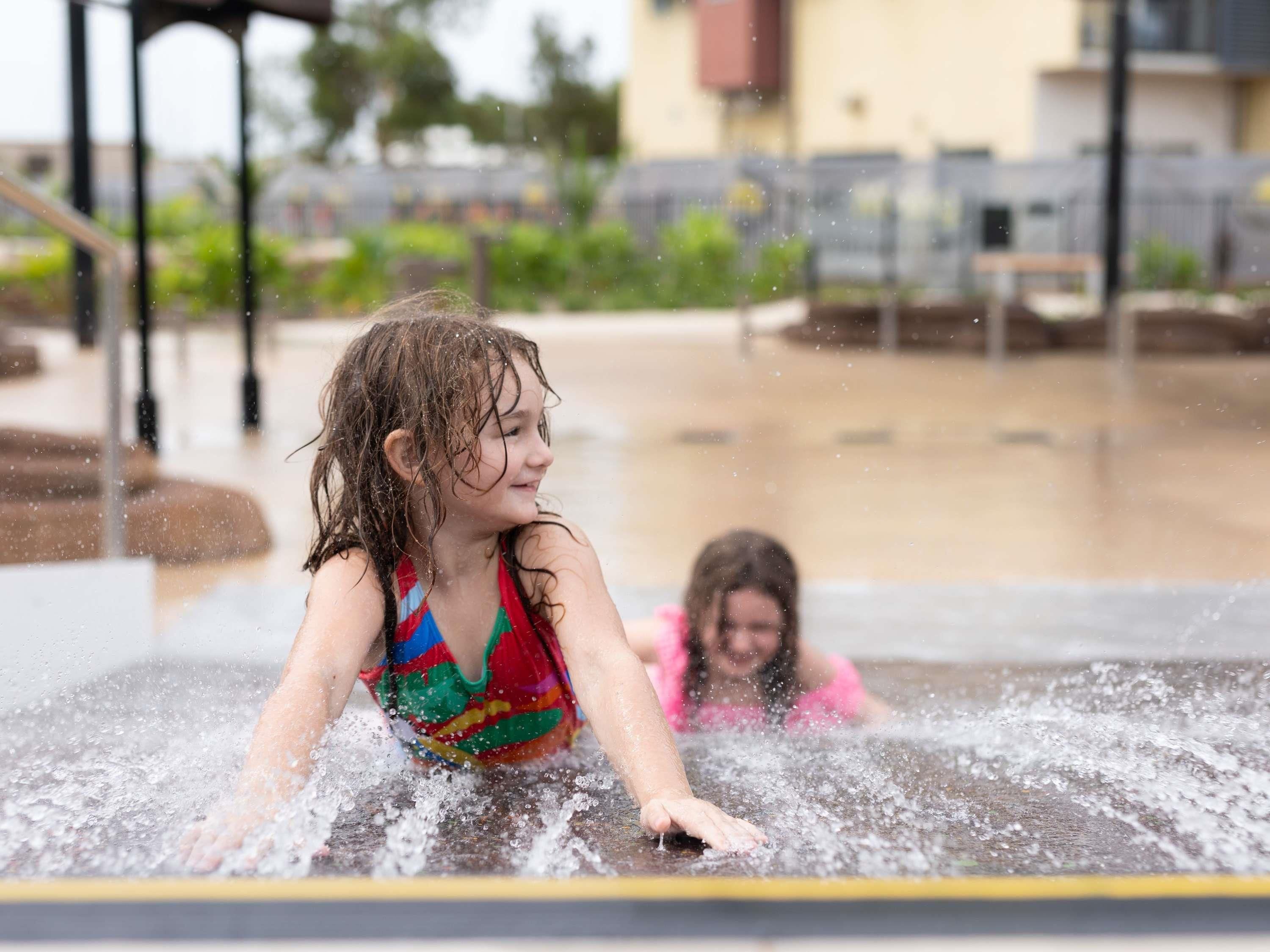 Une fontaine ou un bassin décoratif avec une personne portant un maillot de bain coloré et une autre personne portant un maillot de bain rose.
