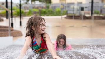 Une fontaine ou un bassin décoratif avec une personne portant un maillot de bain coloré et une autre personne portant un maillot de bain rose.
