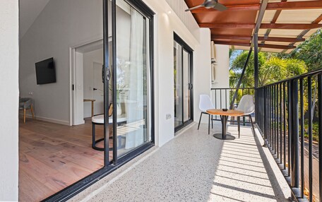 A modern balcony with glass doors, a wooden floor, and a table with chairs.