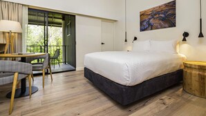 A bedroom with a bed, a desk with a chair, a painting on the wall, and a balcony. - Mercure Darwin Airport Resort (Eaton)