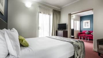 A hotel room with a large bed, a TV, a red sofa, and a red carpet.