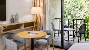 A hotel room with a balcony, a sofa, a table, and a TV.