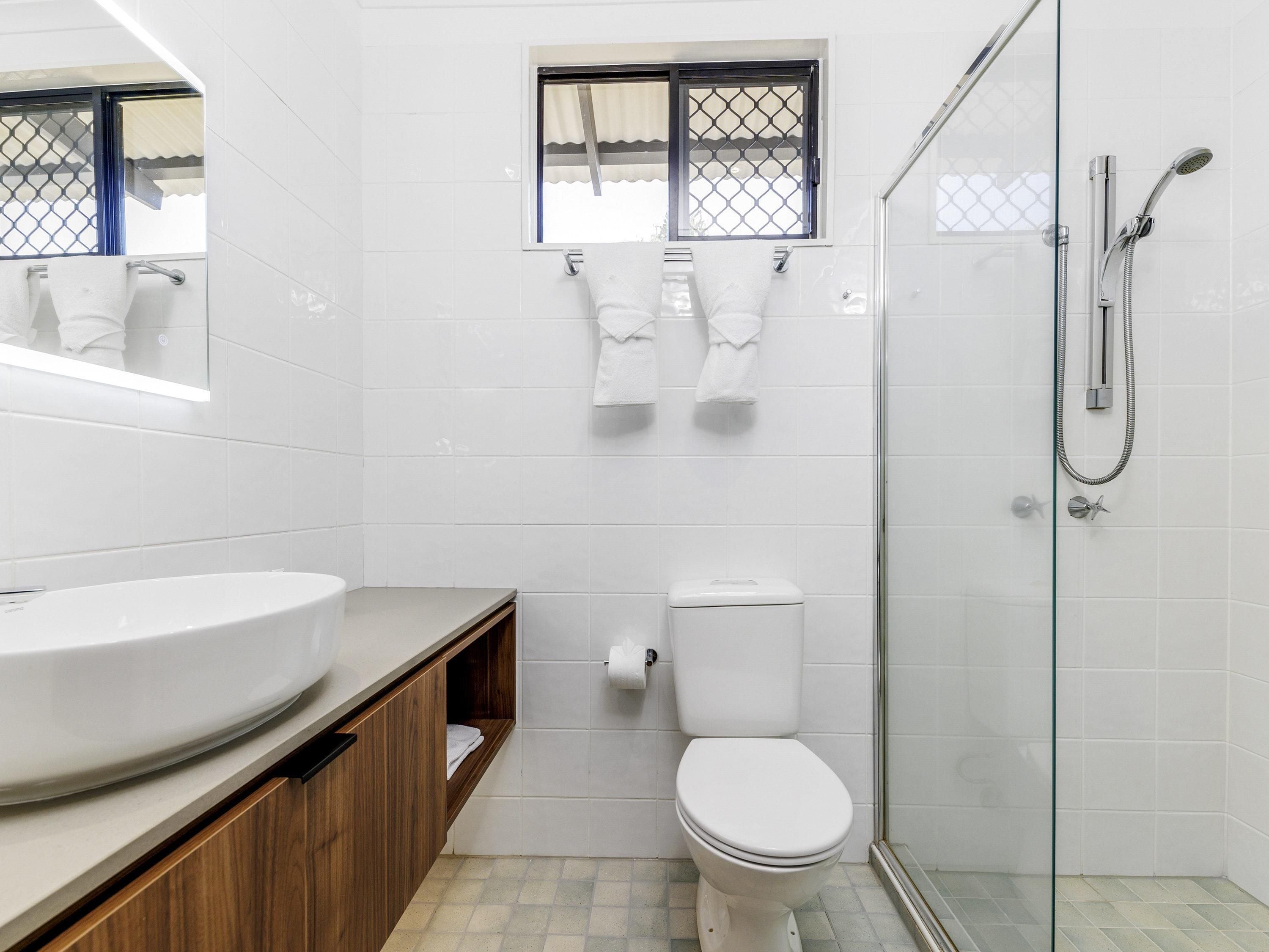A bathroom with a toilet, a sink, and a glass-enclosed shower area.