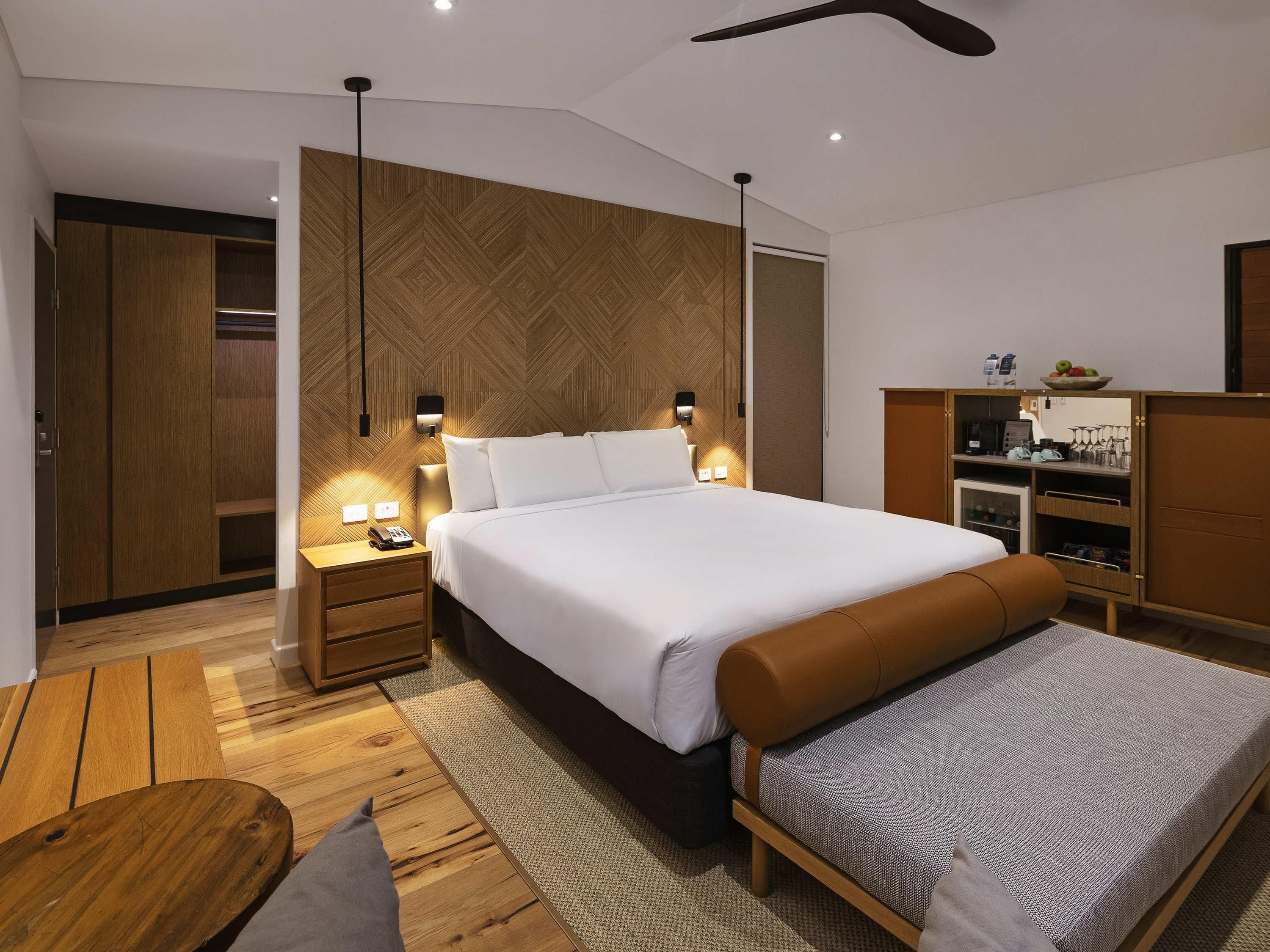 Ein modernes Schlafzimmer mit einem großen Bett, Nachttischen, einem Kleiderschrank und einer eingebauten Sitzbank.