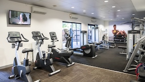 Un gimnasio con cintas de correr, máquinas elípticas y equipamiento de levantamiento de pesas.