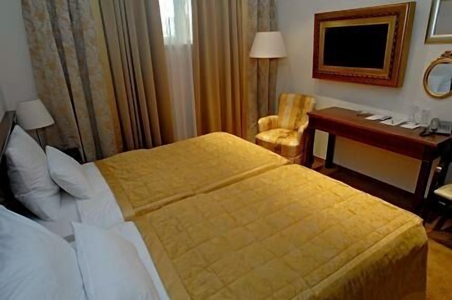 Habitación de hotel con cama doble, escritorio, silla, lámpara y televisión en la pared.