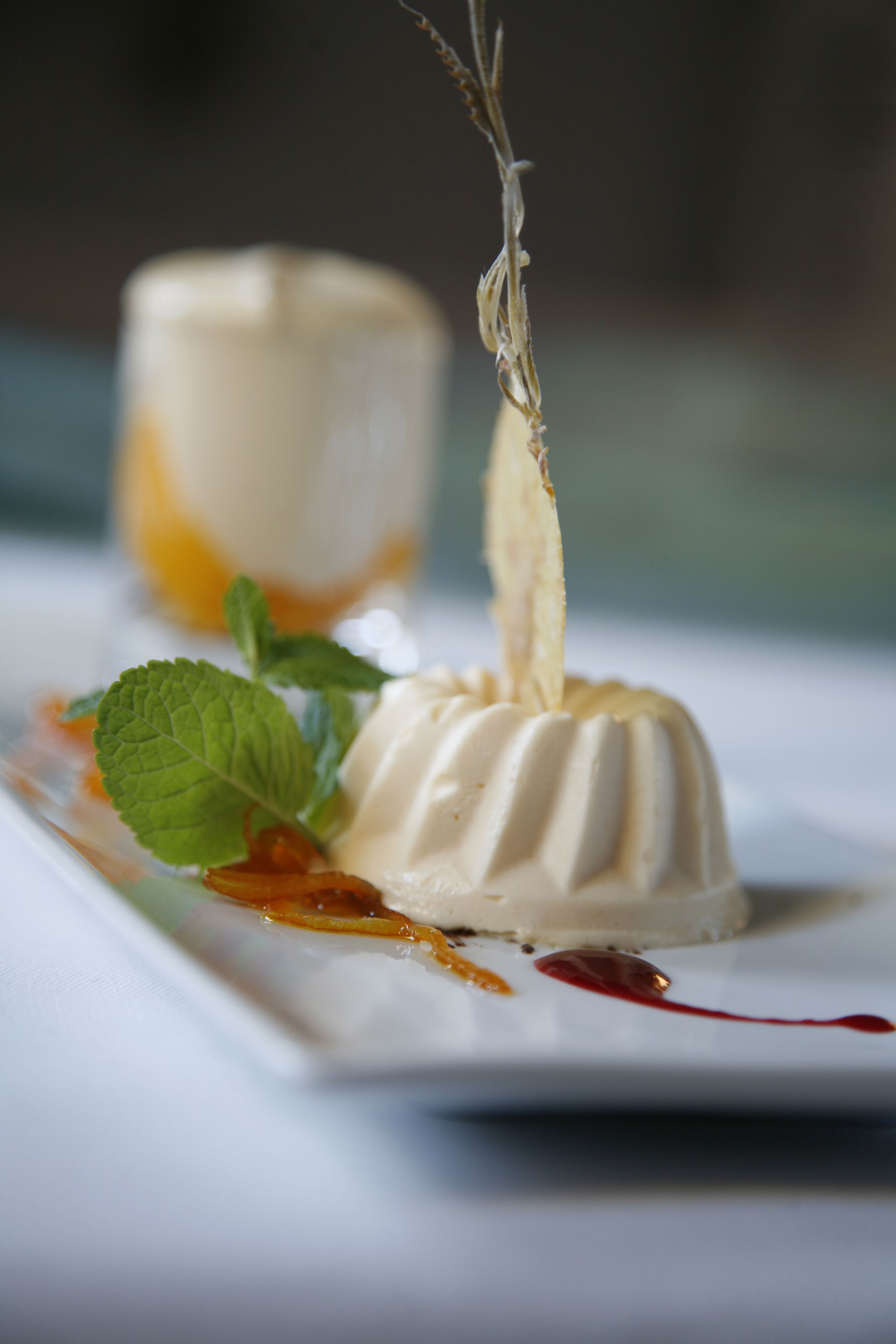 A dessert with a creamy texture, garnished with mint leaves and a decorative element.
