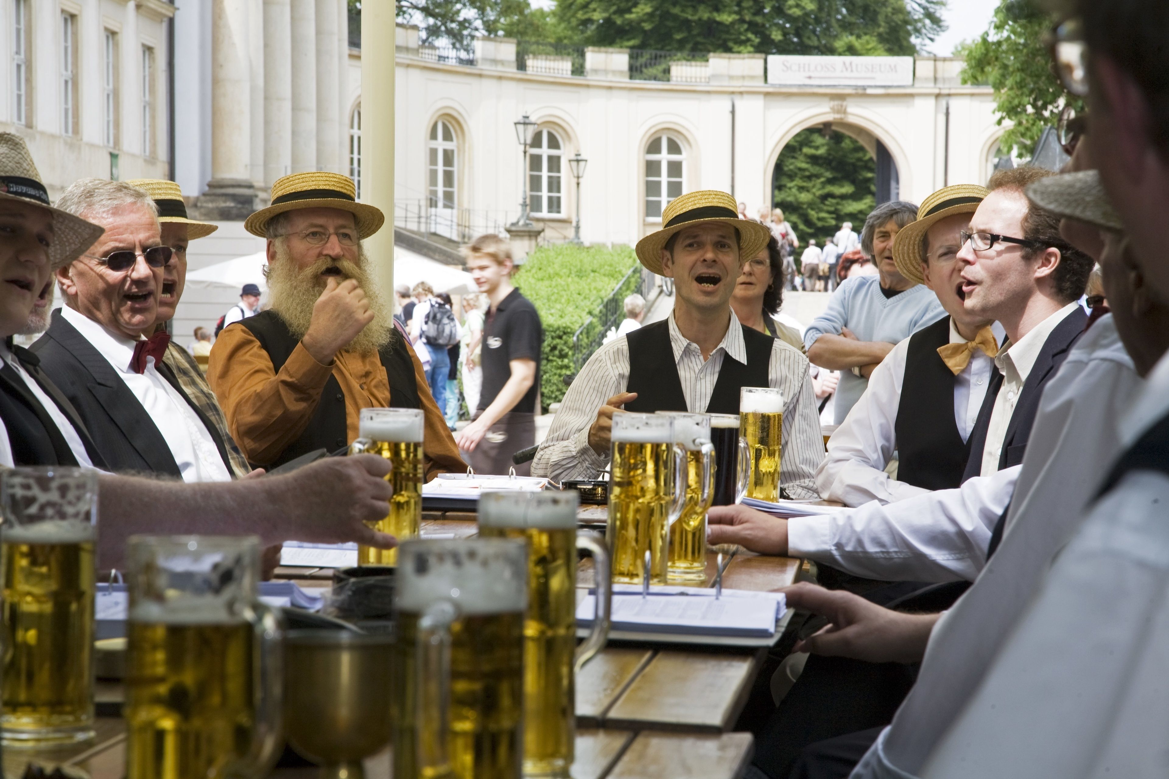 A group of people at an outdoor event, possibly a festival, with beer mugs on a table.