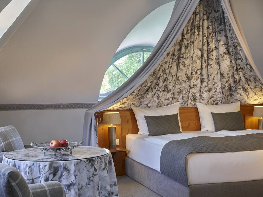 Una camera da letto con un letto a baldacchino, un tavolino con una ciotola di frutta e vista sul verde attraverso la finestra.
