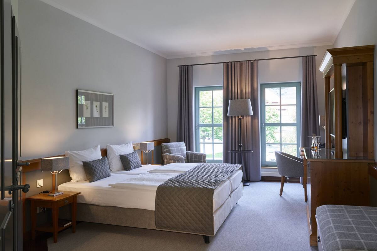 Ein Hotelzimmer mit einem großen Bett, einem Schreibtisch, einem Stuhl, einer Lampe und einem Spiegel.