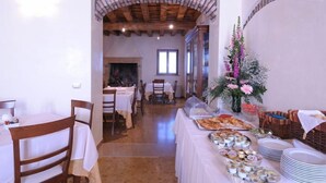 Un espace repas avec des tables dressées pour le service, un buffet proposant divers plats et une composition florale décorative.