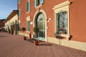 Classic hotel with arched windows and lush greenery.