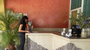 Una recepción con un diseño de mármol, una planta en maceta y folletos sobre el mostrador.