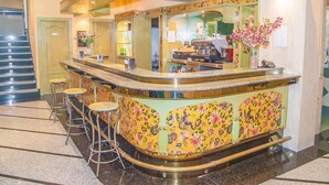 Zona de bar con mostrador curvo, taburetes y un diseño floral en la pared.