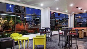 A rooftop bar with yellow chairs, a pool table, and large windows offering city views. - ibis Taubate (Taubate)