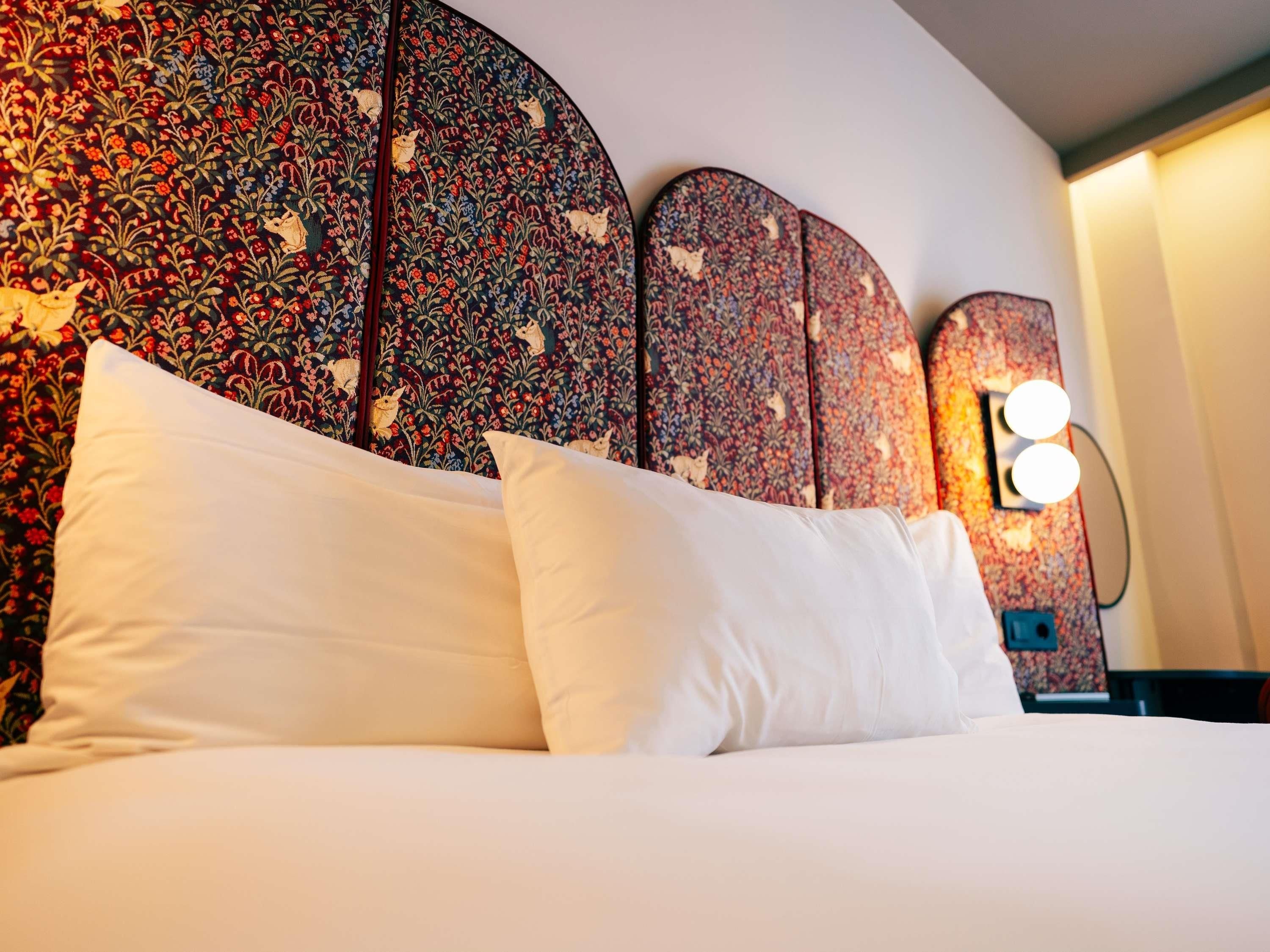 Een bed met witte lakens en een hoofdbord met een bloemenprint.