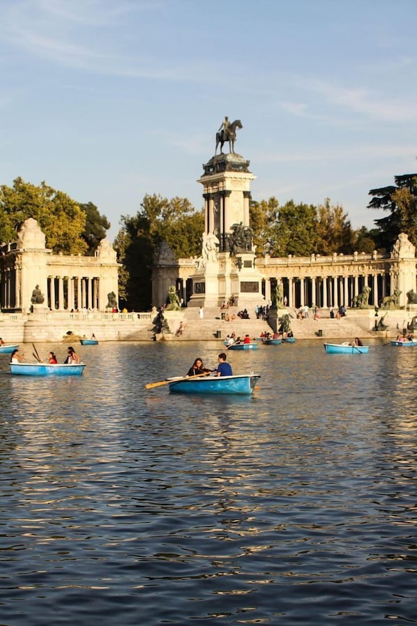 A serene riverside with boats, a statue, and classical architecture. - ibis Styles Madrid Maravillas (Madrid)