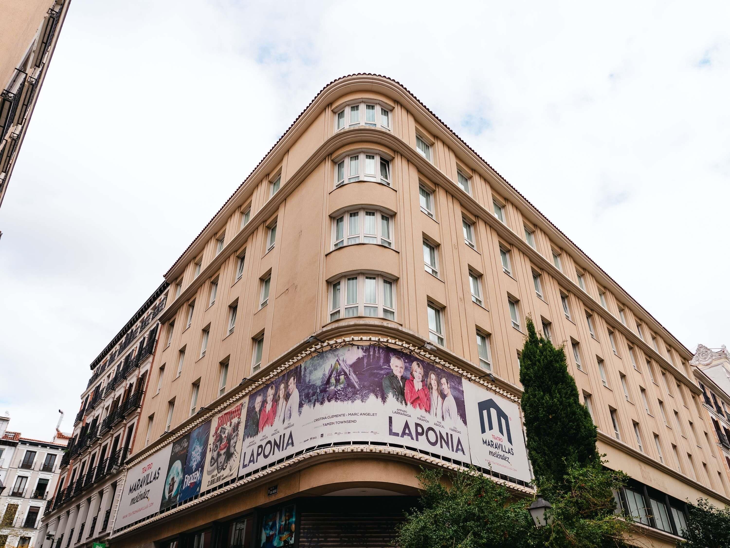 Un edificio de varios pisos con fachada curva, que presenta carteles grandes que anuncian películas y un teatro.
