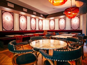 A restaurant interior with round tables, cushioned chairs, and patterned wall panels. - ibis Styles Madrid Maravillas (Madrid)